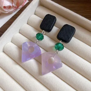 Detail view of handmade wood and resin fan-shaped drop earrings with green crystal beads.