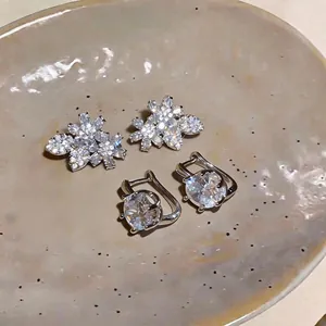 Eleganti orecchini a lobo con fiori in zircone e cerchi in cristallo su piatto di ceramica