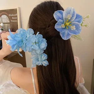 Ethereal blue lily floral hair clip accessory worn on long dark hair