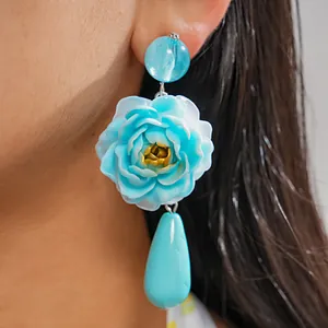Nahaufnahme von blauen Resing-Ohrringen mit Blumenmotiv und Wassertropfen-Anhänger