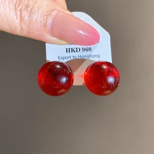Close-up view of elegant red translucent resin round stud earrings with smooth finish