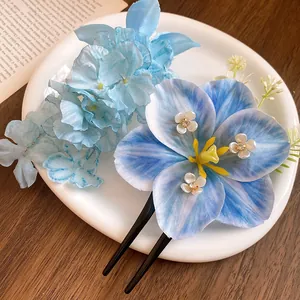 Macro view of blue fabric lily hair pin with rhinestone accents on a white plate