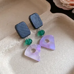 Close-up detail of square wooden studs with green beads and purple resin fan pendants