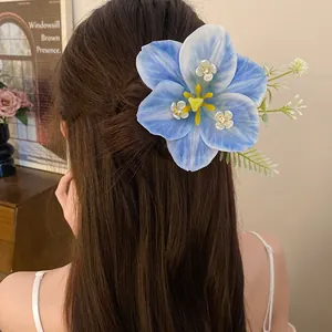 Close-up of a blue lily hair clip with white floral accents on brown hair