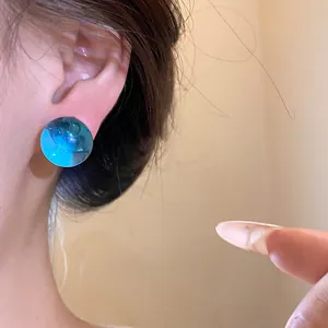 Detailed view of translucent blue resin circular stud earrings on ear for women