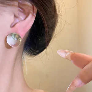 Close-up detail of minimalist round resin earrings with silver needle worn on ear