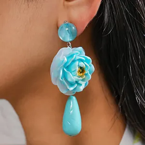Nahaufnahme eines blauen Harzblumenohrrings mit Farbverlauf und Wassertropfenanhänger