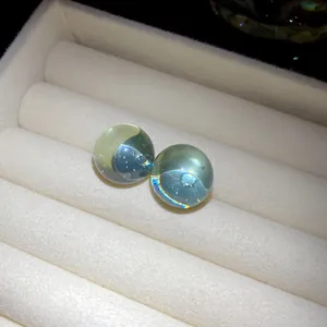 Detailed macro view of round translucent light blue resin stud earrings with silver needles