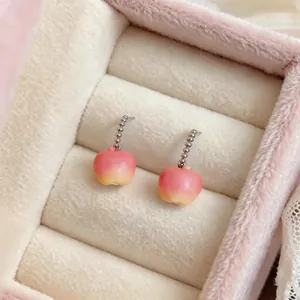 Gros plan de jolies boucles d'oreilles pommes en résine rose avec chaînes argentées.