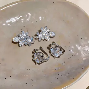 Primo piano di orecchini a fiore in zircone e orecchini a cerchio con pietra grande.