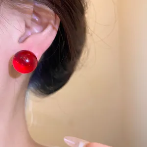 Close-up detail showing the elegant wearing effect of red spherical resin stud earrings