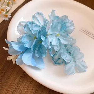 Detail of a blue fabric lily hair clip with delicate beads and a spring aesthetic.