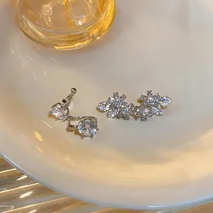 Dettaglio di orecchini a fiore in zircone argento e perni rotondi su un piatto bianco
