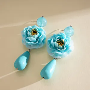 Detailansicht der blauen Harz-Blumenohrringe mit goldenem Herz und Tropfenanhänger.