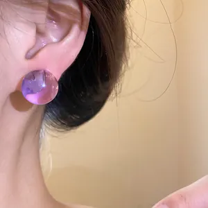 Elegant macro view of a sweet purple round resin stud earring worn on model's ear
