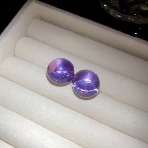 Close-up of purple resin ball stud earrings resting on white velvet jewelry tray