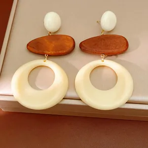 Close-up of vintage geometric earrings featuring wood and cream resin round drops