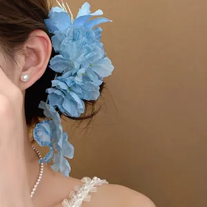 Close-up detail view of an elegant light blue lily flower hair clip worn by a model