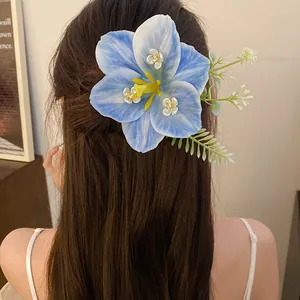 Detail of a large blue lily flower hair clip with yellow stamens on brown hair.