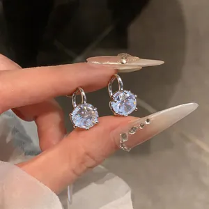 Dettaglio degli orecchini pendenti con zircone tondo scintillante e montatura argento