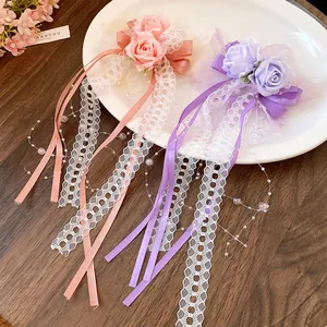 Close-up of romantic lace flower hair clips featuring long ribbon bows and pearls