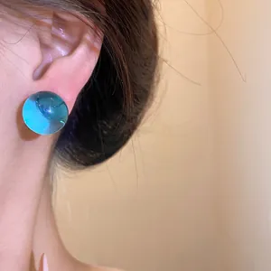 Close-up detail of a minimalist translucent blue resin round stud earring on ear.