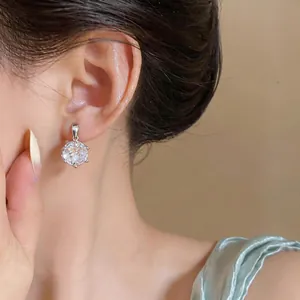 Primo piano di un orecchino a fiore in argento con zircone indossato con eleganza.