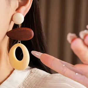Detailed view of vintage style geometric wood and resin hollow drop earrings worn by model