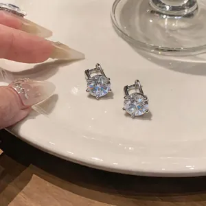 Dettaglio ravvicinato di eleganti orecchini a perno in zircone argento su un piatto di ceramica