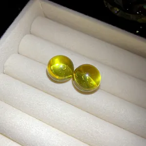 Detailed macro view of translucent lime yellow resin round stud earrings in white tray