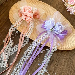 Detail view of purple and pink lace flower hair clips with long elegant ribbon streamers.