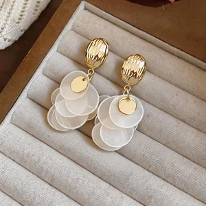 Detailed macro shot of vintage French style gold earrings with shell petal tassels