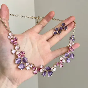 Detailed view of floral necklace and earrings set with purple and pink enamel finish