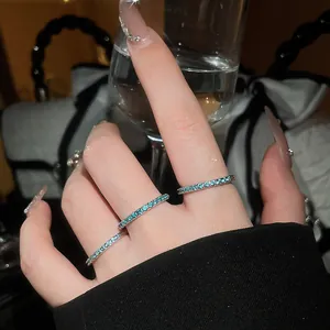 Detailed macro view of three slim stackable rings with mint green zircons on a hand