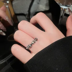 Close-up view of a silver zircon stackable ring worn on a finger in a dark setting.