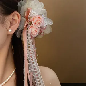 Elegant detail of a lace flower hair clip featuring pink roses and decorative ribbons