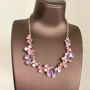 Close-up of elegant pink and purple painted flower necklace on a brown display bust