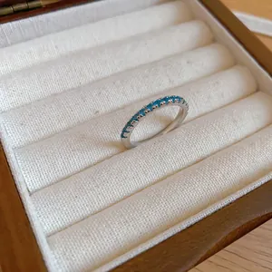 Detailed macro view of a thin silver eternity ring set with mint green zircon stones.