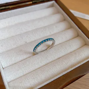Elegant close-up of a minimalist silver eternity ring with vibrant blue zircon stones