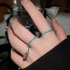 Close-up of elegant mint green zircon pavé rings and silver charm ring on finger.