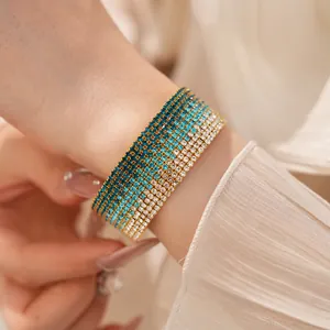 Primo piano di un elegante bracciale elastico multistrato con strass sfumati al polso.