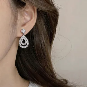 Detailed close-up of elegant teardrop dangle earrings with zircon flower stud on ear model