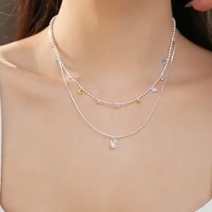 Dettaglio di una collana d'argento a due strati con ciondoli in zircone colorati su modella