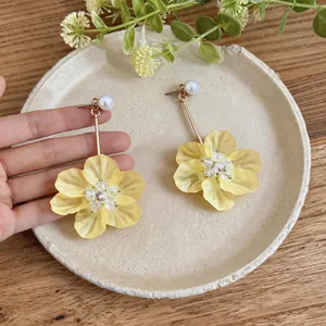 Macro view of sweet yellow resin flower dangle earrings with pearl stud and gold rod detail.