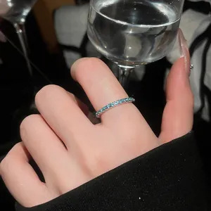 Macro detail of a thin mint green zircon pavé ring on a finger with sophisticated lighting.