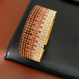 Dettaglio ravvicinato di lussuoso bracciale aperto multifila con strass sfumati oro