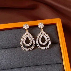 Detailed macro view of gold-plated teardrop earrings with sparkling white cubic zirconia stones