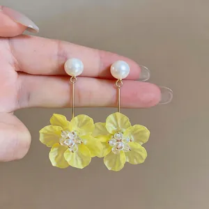 Detail of yellow translucent flower drop earrings with white pearl studs
