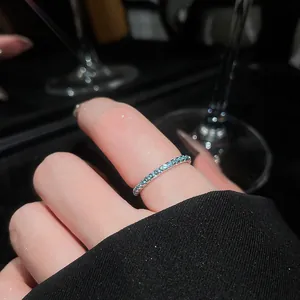 Close-up of a mint green zircon row ring on finger with elegant silver band detailing.