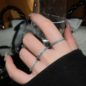 Close-up of three mint green zircon eternity rings on hand holding a crystal glass